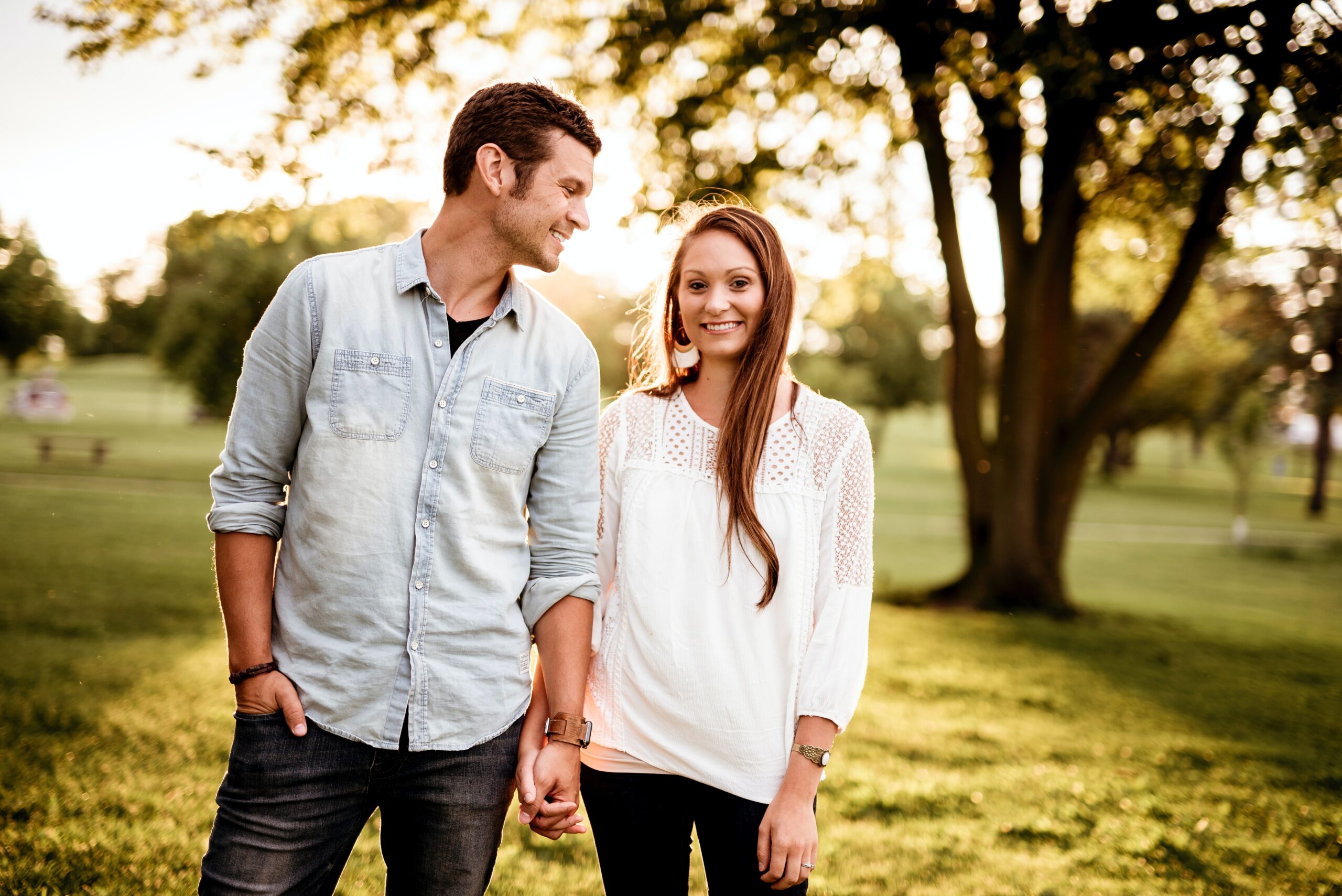 man and woman holding hands smiling in a field