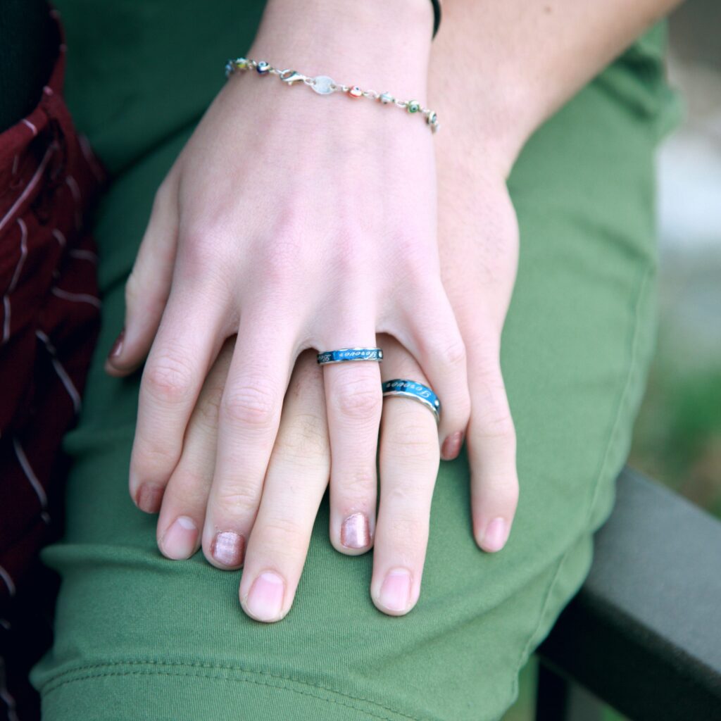 two hands on top of eachother with blue rings