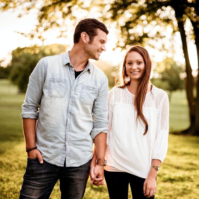 man and woman holding hands smiling in a field